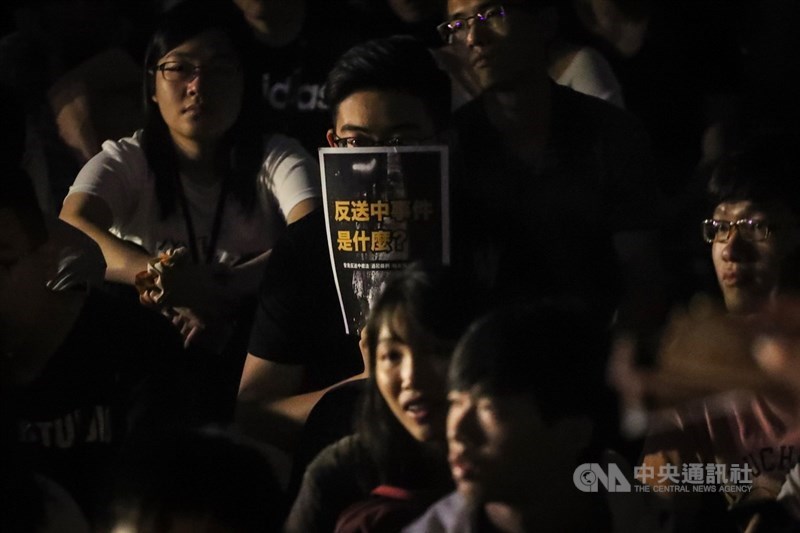 香港人民走上街頭表達「反送中」立場,台灣大學學生14日晚間在台大傅鐘前發起「台大撐香港-台大人反送中之夜」活動,現場學生拿著反送中宣傳單聆聽台上發言。中央社記者裴禛攝 108年6月14日