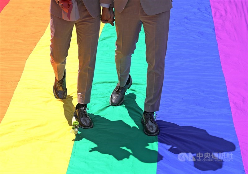 同婚登記5月24日開跑,同婚團體婚姻平權大平台在台北市信義區戶政事務所外舉辦「幸褔起跑線Wedding Party」,同志新人盛裝出席,以彩虹旗當作紅毯步入會場。(中央社檔案照片)