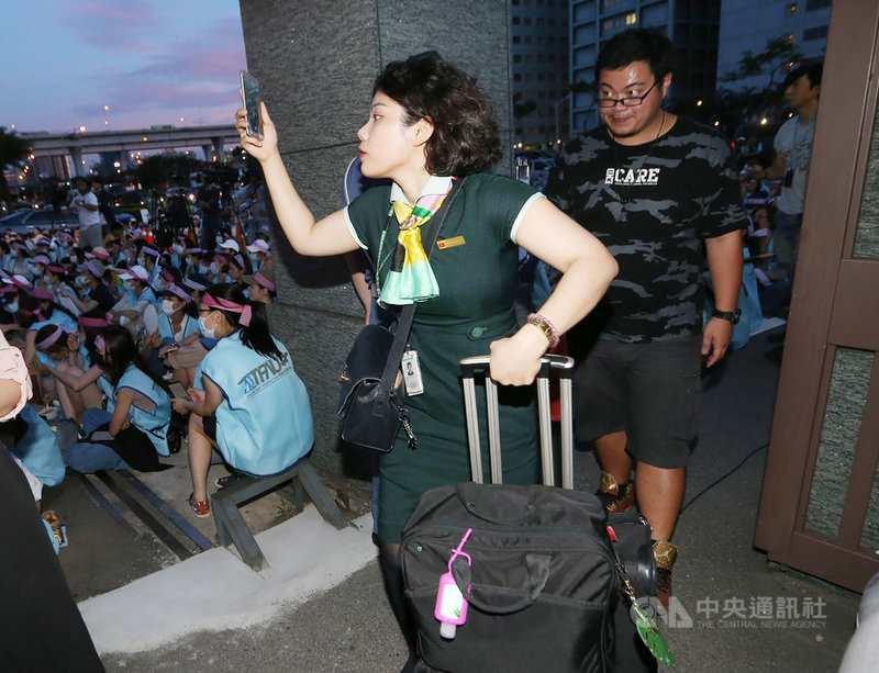 長榮航空部分空服員展開罷工,參與成員20日下午起陸續到桃園南崁長榮運航大樓門口靜坐,有值勤空服員經過時不忘拿著手機拍下正在罷工的同事。中央社記者鄭傑文攝 108年6月20日