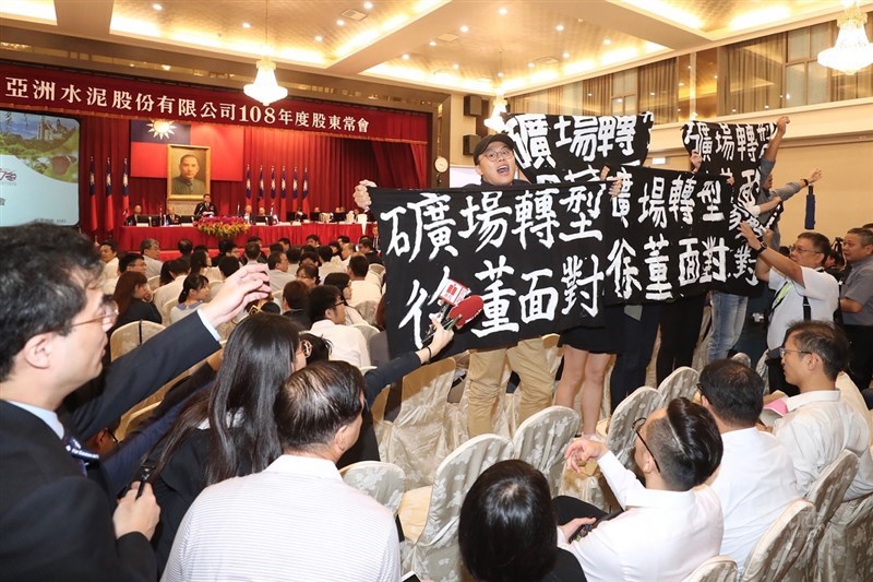 「地球公民基金會」及「反亞泥,還我傳統領域自救會」8名環團人士,24日進入亞泥股東會場內拉布條抗議,向亞泥董事長徐旭東(後左3)高喊「礦場轉型.徐旭東面對」等口號。中央社記者吳翊寧攝 108年6月24日