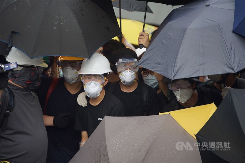 香港主權移交22週年,官方預定1日早上8時舉行升旗典禮,一群反對港府修訂逃犯條例的示威者試圖阻止升旗儀式進行,示威者穿戴防護裝備,以雨傘阻擋警方噴灑辣椒水。中央社記者裴禛香港攝 108年7月1日