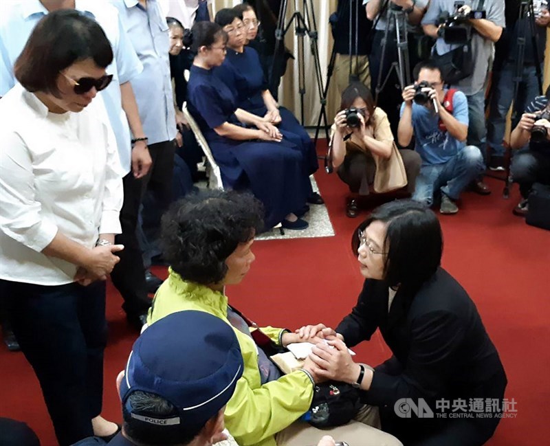 總統蔡英文(前右黑衣者)4日下午親自前往嘉義市立殯儀館,慰問因公殉職的鐵路警察李承翰家屬,蹲下身來緊握李承翰母親的手。中央社記者黃國芳攝 108年7月4日