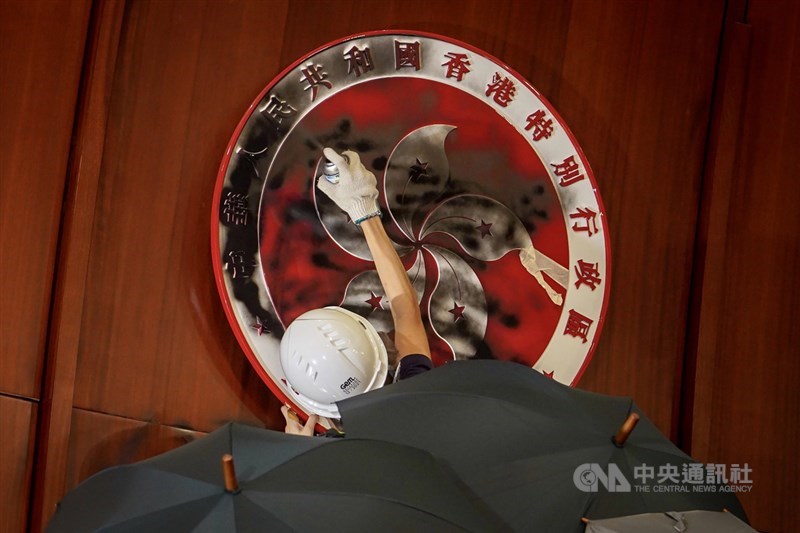 大批香港示威者1日晚間撬開立法會鐵門後進一步占領議場,1名示威者將會議廳內的特區政府區徽塗黑。中央社記者裴禛香港攝 108年7月1日
