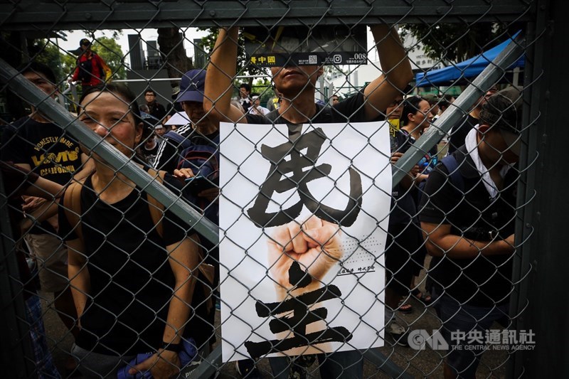 香港民眾11日下午在維多利亞公園舉行反送中集會,有民眾手持印有「民主」的標語,出席集會表達訴求。中央社記者吳家昇攝 108年8月11日
