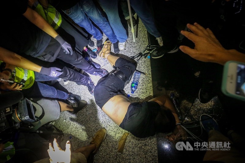 反送中示威者13日持續在香港機場集會,14日凌晨0時,環球時報記者付國豪(倒地者)被參加反送中集會的示威者包圍,並綁住雙手雙腳。中央社記者吳家昇攝 108年8月14日