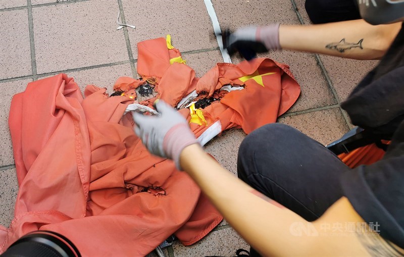 香港反送中人士21日下午舉行遊行,其中有人在屯門大會堂旁拉下中國國旗並燒燬。(中央社檔案照片)
