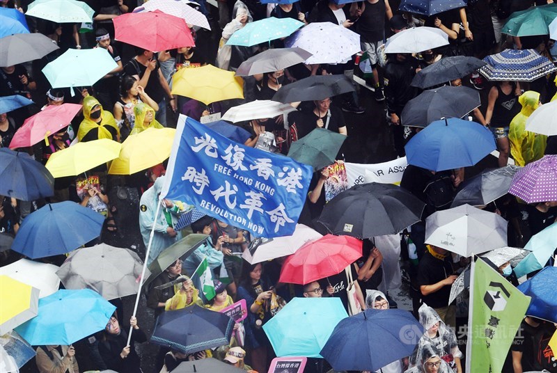 「929台港大遊行:撐港反極權」活動29日下午在立法院旁登場,許多民眾撐傘、穿雨衣到場參與,遊行隊伍中還有人高舉「光復香港 時代革命」旗幟,表達立場。中央社記者施宗暉攝 108年9月29日