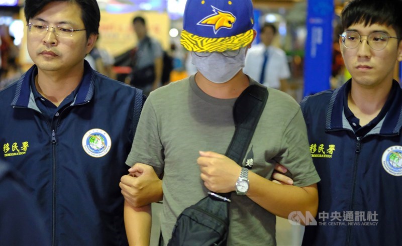 30歲中國籍李姓男子(中)涉嫌撕毀台大校內連儂牆所貼的反送中海報,被依法強制出境,晚間在移民署人員陪同下搭機離境。中央社記者邱俊欽桃園機場攝 108年10月8日