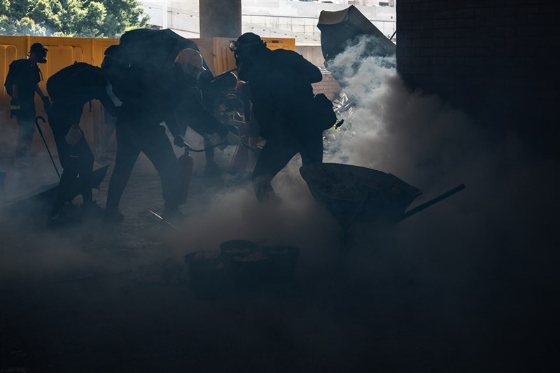香港反送中群眾11日發起「三罷」活動,防暴警察進入香港中文大學和理工大學校園追捕黑衣示威者,並發射催淚彈。圖為理工大學學生在警方施放催淚彈後,使用滅火器撲滅。(法新社提供)