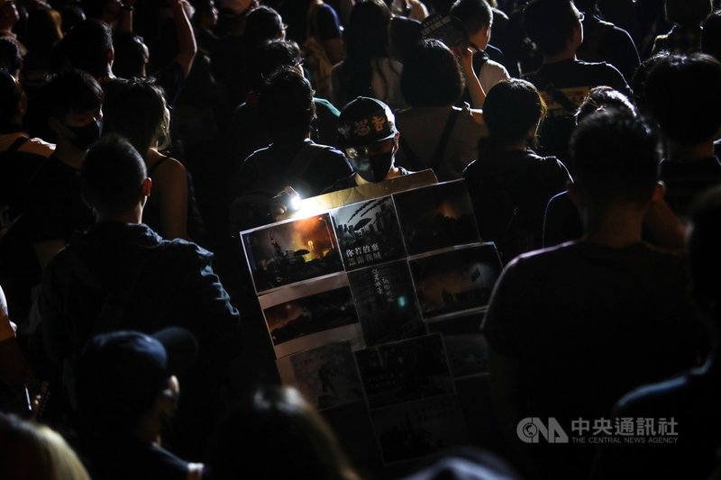 撐香港要自由演唱會17日晚間在台北自由廣場登場,不少人帶著各式旗幟、標語等到場響應,有與會民眾在人群中手持貼滿香港抗爭過程照片的看板,表態力挺香港反送中運動。中央社記者吳家昇攝 108年11月17日
