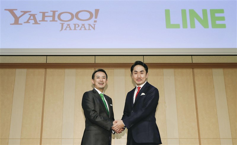 雅虎日本母公司ZHD與LINE 18日宣布將進行合併,成日本境內最大IT企業。圖為ZHD社長川邊健太郎(左)與LINE社長出澤剛在記者會上握手。(共同社提供)