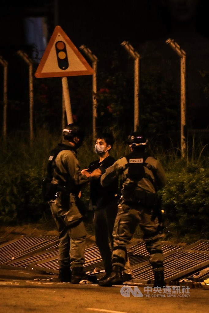 香港理工大學內的反送中示威者持續被港警包圍,至19日深夜校內所剩抗爭民眾已不多,有黑衣民眾(中)欲闖越封鎖線撤離,遭警方發現後攔截逮捕。中央社記者吳家昇攝 108年11月19日