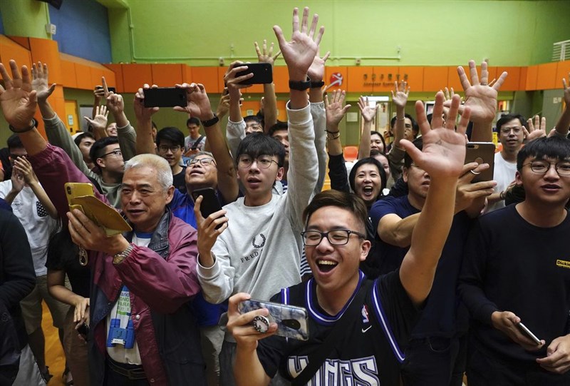 香港泛民主派在區議會選舉中大獲全勝,篤定將可以取得特首選舉委員會1200席中的117席。圖為泛民派候選人確定當選後,支持者歡呼慶祝。(美聯社)