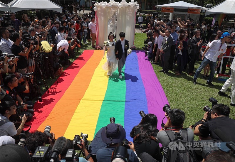 立法院三讀通過司法院釋字第748號解釋施行法,台灣成為亞洲第一個同性婚姻法制化國家,中央通訊社評選此為2019年國內10大新聞的第一名。圖為5月24日同婚登記開跑,同志新人以彩虹旗當作紅毯步入會場。(中央社檔案照片)