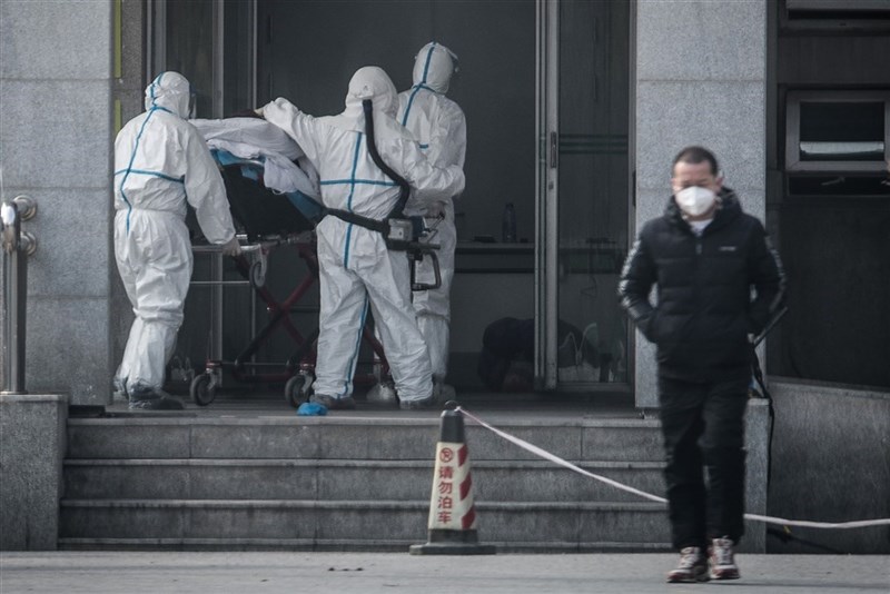 武漢市肺炎疫情防控指揮部已發布通告表示,自23日上午10時起,全市公車、地鐵、輪渡、長途客運暫停運營。圖為醫護人員將患者送入武漢金銀潭醫院。(法新社提供)