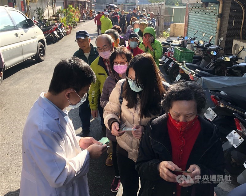中國武漢肺炎疫情引發口罩搶購潮,口罩實名制6日上路,台北市一家藥局一早就有民眾在外等候,還未開門就大排長龍,藥劑師發放號碼牌給排隊民眾。中央社記者王飛華攝 109年2月6日
