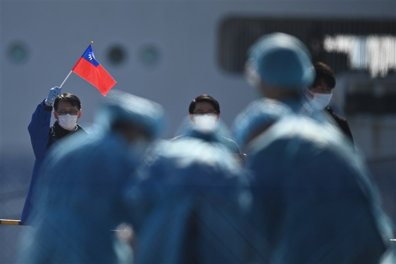 鑽石公主號包機21日晚間抵台，預計接回20名台灣人。圖為台灣籍乘客下船時揮舞國旗。（法新社提供）