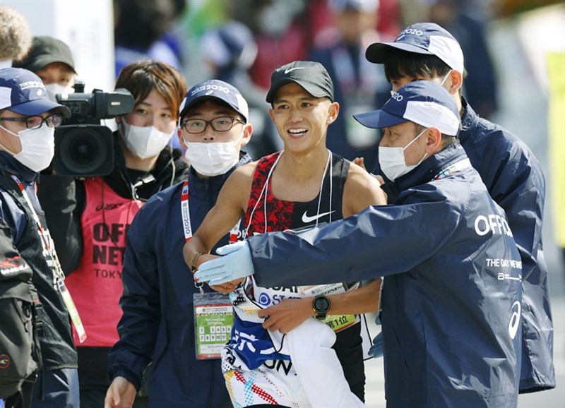 日本境內武漢肺炎疫情持續延燒,東京馬拉松主辦單位日前取消一般跑者參賽,只讓菁英選手下場,現場可見工作人員配戴口罩。(共同社提供)