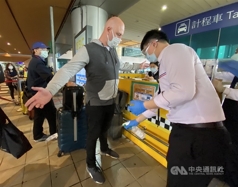 所有入境旅客從19日起均需居家檢疫14天,旅客搭乘防疫專車前需經過消毒作業。中央社記者邱俊欽桃園機場攝 109年3月19日