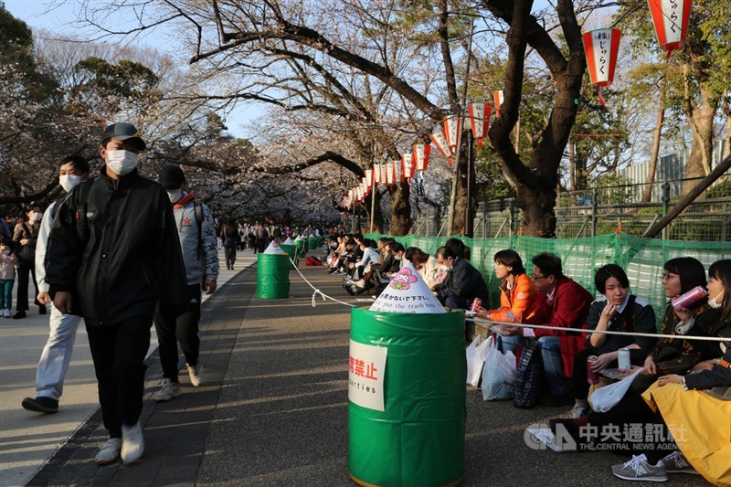 受到武漢肺炎疫情影響,日本多處賞櫻景點不得辦櫻花宴,東京上野恩賜公園地面或告示塔寫著「禁止宴席」。有遊客坐著邊喝啤酒邊賞櫻。中央社記者楊明珠東京攝 109年3月22日