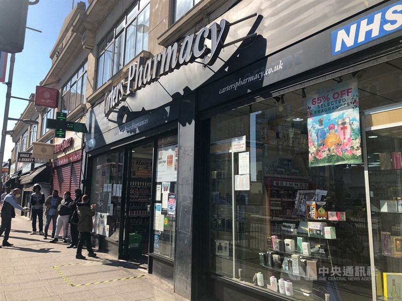 英國下禁足令後,僅有少數店家獲准開業,照片為倫敦的藥局外排起人龍。中央社記者戴雅真倫敦攝 109年3月27日