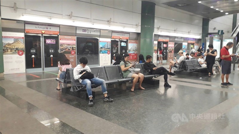 新加坡推動改變社交習慣的保持安全距離措施,地鐵站裡民眾在等候地鐵進站的座位區也相隔而坐,保持安全距離。中央社記者黃自強新加坡攝 109年3月30日