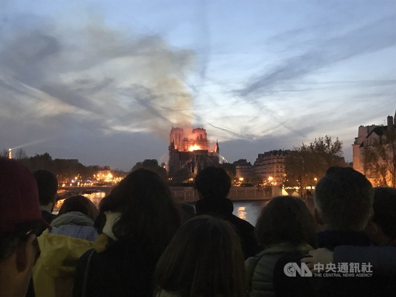 巴黎聖母院2019年4月發生大火,周圍人行道、橋上、河堤邊站滿許多人,神情肅穆、不發一語地看著火光與濃煙侵略這座存在超過850年的歷史建築。(中央社檔案照片)