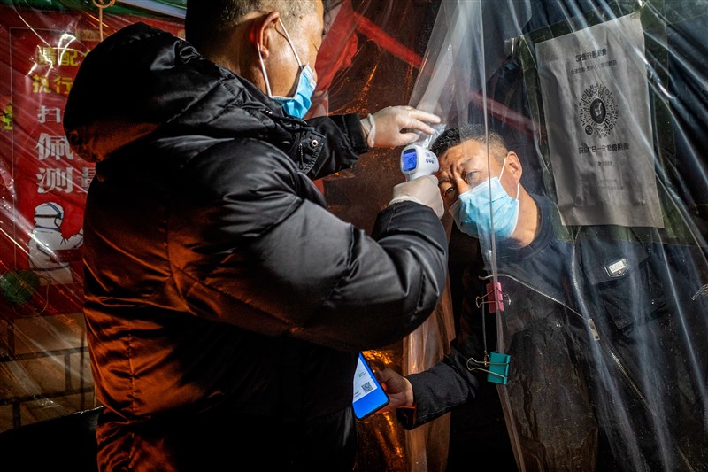 中國黑龍江省牡丹江市一間醫院日前爆發武漢肺炎群聚感染,已有14人染疫。圖為黑龍江省牡丹江市社區工作人員幫民眾量測體溫。(法新社提供)