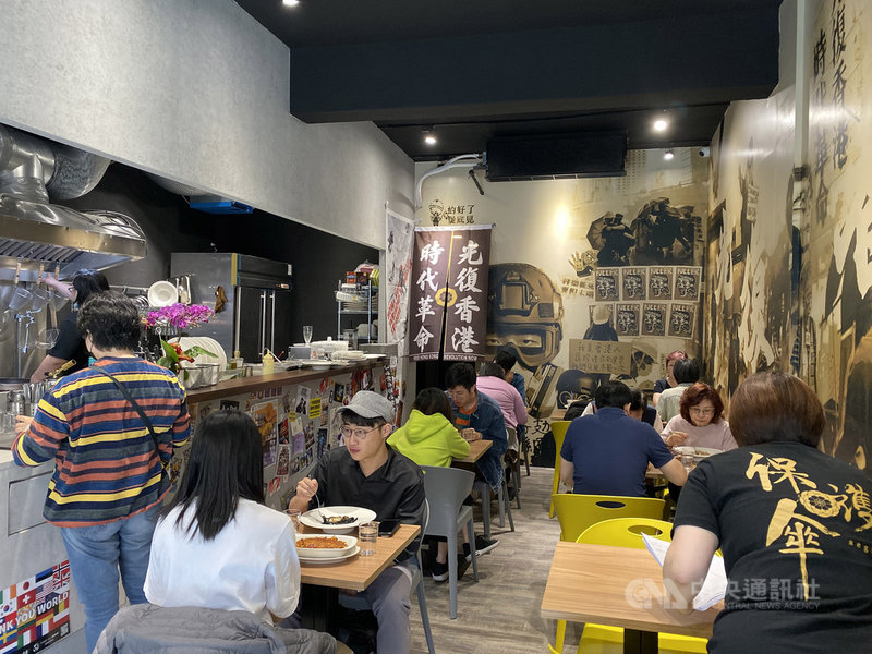 位於台北的「保護傘」餐廳內,隨處可見「反送中」運動的元素,牆上是巨型的抗爭插畫,而寫上「光復香港,時代革命」標語的門簾,就掛在店內醒目的位置。中央社記者賴言曦攝 109年4月29日