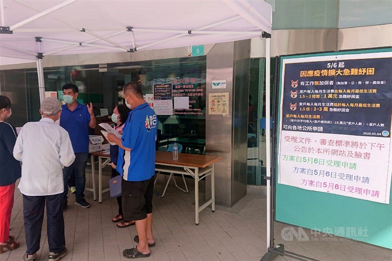 因應疫情擴大急難紓困6日開始申請,台南市仁德區公所除了在門口張貼說明,也派員對民眾解說需準備的相關資料。中央社記者楊思瑞攝 109年5月6日