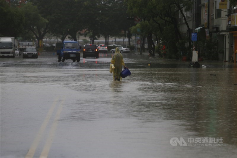受滯留鋒面及西南氣流影響,高雄市區22日下起滂沱大雨,鹽埕區七賢抽水站有一台抽水機故障,造成大公路、富野路一帶無法排水,民眾拿著水桶在雨中前行。中央社記者董俊志攝 109年5月22日