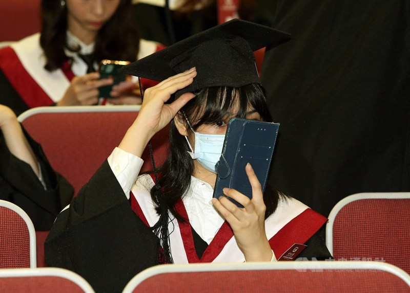世新大學採梅花座防疫,畢業生即使妝容都被口罩遮掩,還是不忘透過手機前鏡整理外表。中央社記者郭日曉攝 109年6月6日