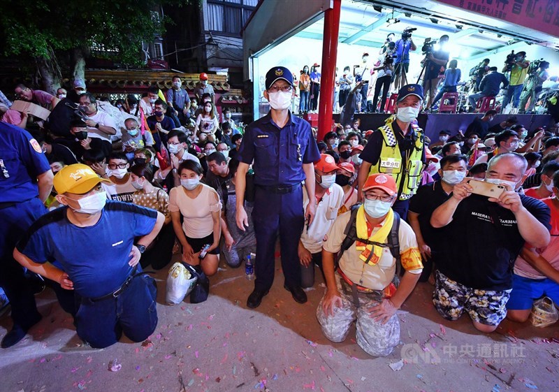 台中大甲媽祖11日深夜起駕遶境,鎮瀾宮前廣場擠滿戴口罩的信眾,跪地恭迎媽祖鑾轎。現場待命維持秩序的員警也戴著口罩值勤。中央社記者王飛華攝 109年6月11日
