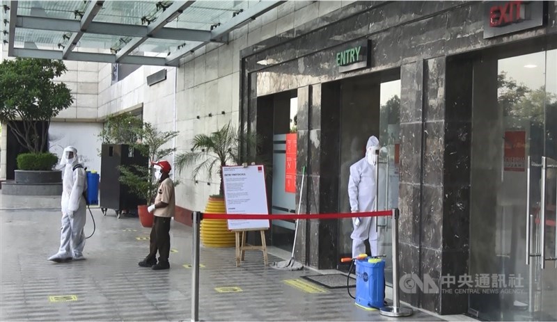 南德里恩比恩斯購物中心門口檢測體溫人員及背著消毒水的人,8日在印度三階段解封首日對外開放營業時,穿著覆蓋全身的防護衣。中央社記者康世人新德里攝 109年6月9日