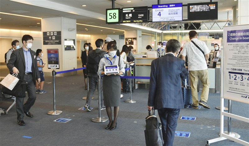 日本外務大臣茂木敏充19日表示,已與越南談妥,兩國商務人士在符合條件下可入境。圖為羽田機場登機門旅客排隊保持社交距離。(示意圖/共同社提供)