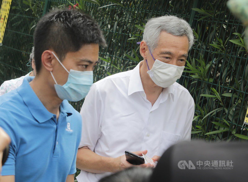 新加坡10日舉行國會大選,總理李顯龍夫婦赴雅德小學投票站投票。圖為李顯龍(右)在投票站外與其他選民依序排隊進入投票站。中央社記者黃自強新加坡攝 109年7月10日