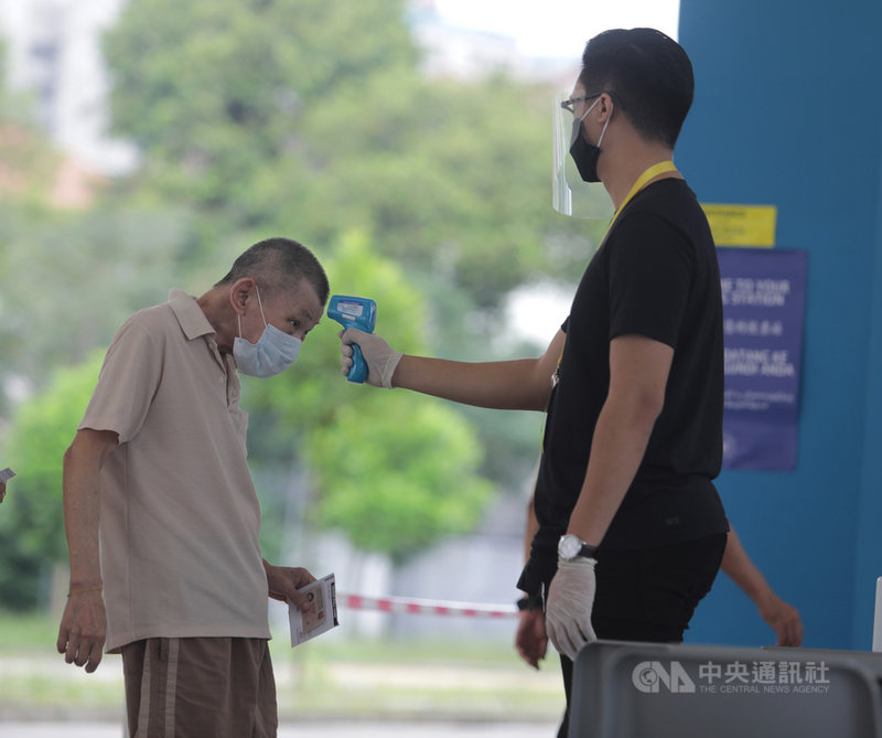 新加坡10日在疫情下舉行國會大選,選民進入投票站投票前要測量體溫,確認是否出現發燒或呼吸系統不舒服等症狀。中央社記者黃自強新加坡攝 109年7月10日