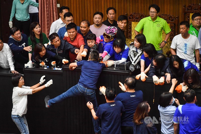 國民黨立委占據立院主席台表達對監院人事案的抗議,民進黨立委16日下午展開強勢清場,藍委洪孟楷(中攀爬者)試圖爬上主席台堅守。中央社記者林俊耀攝 109年7月16日
