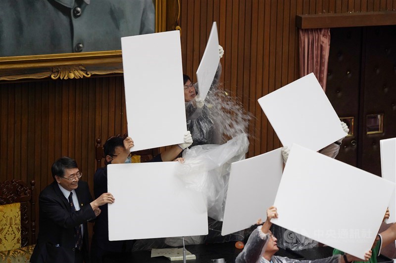 立法院會17日進行監察院人事同意權案投票,中午開票前,國民黨立委拿出預藏的水球,往主席台及票匭處猛丟,企圖阻止開票進行;民進黨立委則穿上雨衣,以保麗龍板保護立法院長游錫堃。中央社記者徐肇昌攝 109年7月17日