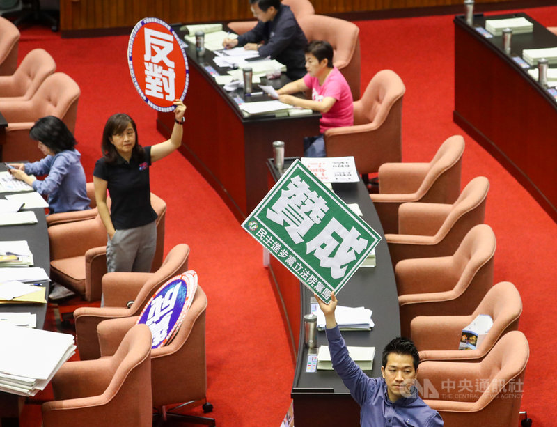 立法院會21日繼續處理國民參與刑事審判法草案等,修正條文表決過程,民進黨立委何志偉(前)與國民黨立委林奕華(後)分別舉贊成、反對看板,兩黨意見分歧。中央社記者王騰毅攝 109年7月21日