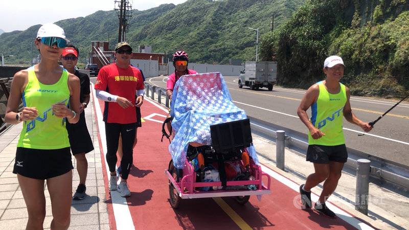 單親媽媽陳嘉齡(後右)帶著罹患腦性麻痺的兒子「小比」環島,23日上午行經基隆市八斗子,國民黨籍市議員張淵翔(紅衣者)等人前往陪跑。中央社記者王朝鈺攝 109年7月23日