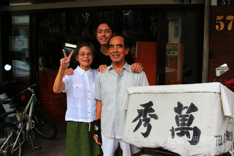 經營萬秀洗衣店的張萬吉（右）與許秀娥（左），在孫子張瑞夫（中）鼓舞下，穿上店內客人遺留的無主衣拍照並上網分享，意外引發外媒關注。中央社記者蘇木春攝　109年7月25日
