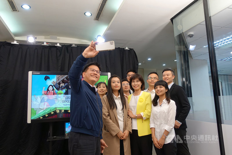 高速公路局國道路況播報團隊26日下午首度亮相，宣告正式成軍，交通部長林佳龍（左）與中央氣象局資深預報員伍婉華（黃色外套者）到場為團隊打氣，開心玩起自拍。中央社記者沈佩瑤攝　109年9月26日