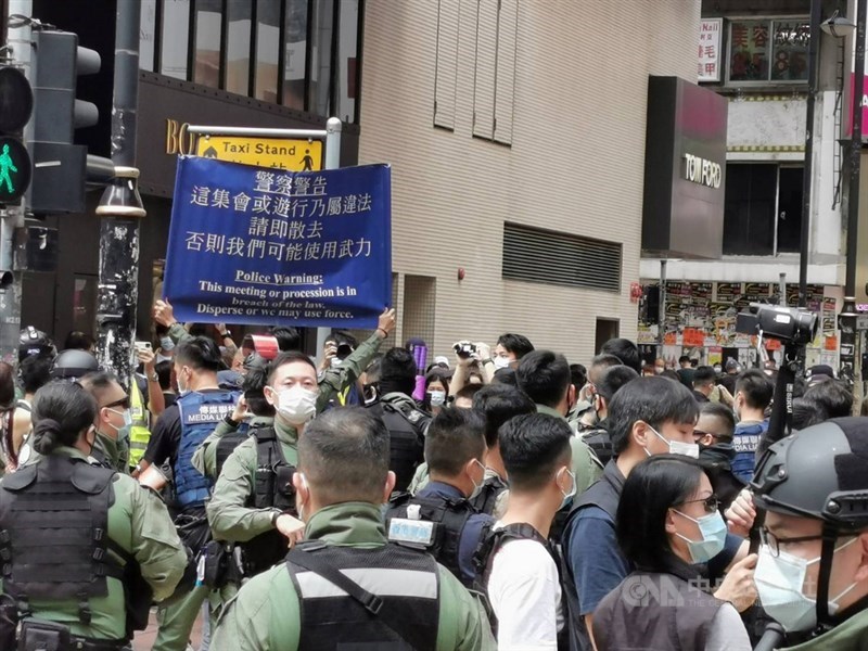 香港網友1日發起多區集會遊行,銅鑼灣東角道一帶,有數百名防暴警察戒備,不時驅趕個別穿黑衣示威者。圖為防暴警察舉起藍旗,警告市民不要聚集。中央社記者張謙香港攝 109年10月1日