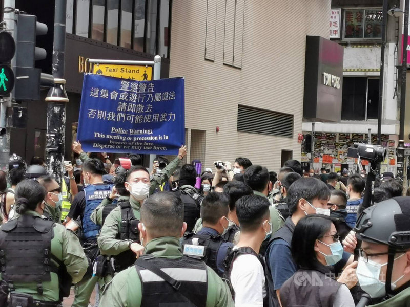 香港網友1日發起多區集會遊行,但至下午1時尚無大規模集結。銅鑼灣東角道一帶,有數百名防暴警察戒備,不時驅趕個別穿黑衣示威者。圖為防暴警察舉起藍旗,警告市民不要聚集。中央社記者張謙香港攝 109年10月1日