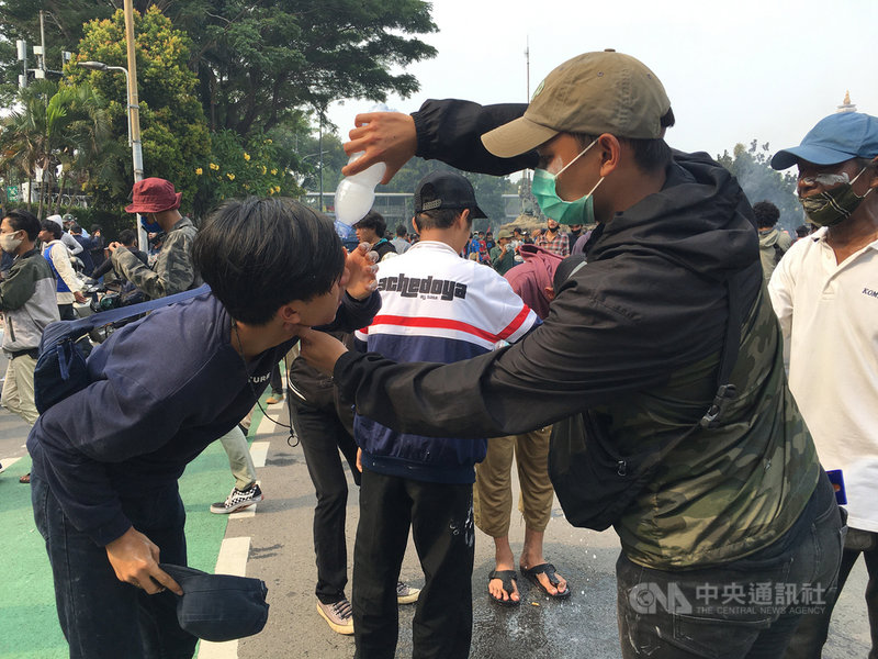 印尼大學生8日走上街頭抗議勞動法案，遭警方發射催淚瓦斯驅離，現場有學生眼睛不適，其他學生用水幫忙沖洗眼睛。中央社記者石秀娟雅加達攝 109年10月8日