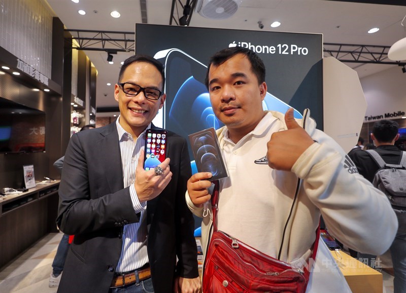 蘋果iPhone 12、12 Pro 23日在台灣正式開賣,搶到台灣大哥大頭香的民眾陳先生(右),特地請兩天假排隊,拿到到新機後與台灣大哥大總經理林之晨(左)開心合影。中央社記者裴禛攝 109年10月23日
