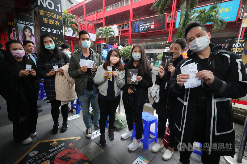 蘋果iPhone 12系列23日在台開賣,不畏低溫降雨、果粉漏夜苦等,拿到號碼牌後開心合影留念。中央社記者裴禛攝 109年10月23日