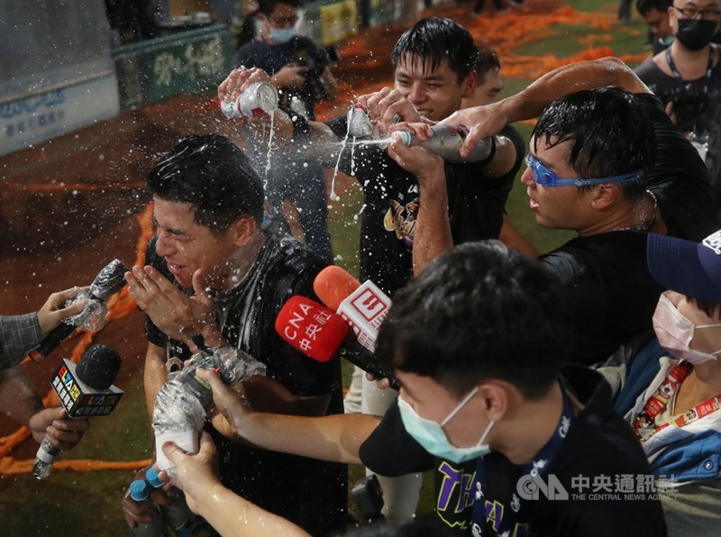 中職統一7-ELEVEn獅隊24日以3比2擊敗中信兄弟隊,奪下中職31年下半季冠軍,在台南主場拋下橘色彩帶,賽後陳傑憲(左)受訪時,被隊友以飲料突襲潑灑慶祝。中央社記者張新偉攝 109年10月24日