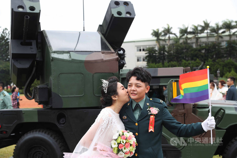 陸軍30日舉辦聯合婚禮,同婚官兵陳瑩宣(右)與妻子李沴稹(左)持彩虹旗在復仇者飛彈車前合影。中央社記者游凱翔攝 109年10月30日